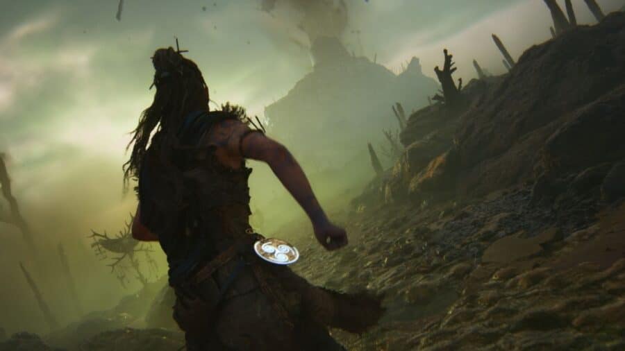 Scena cupa di Hellblade con la protagonista vista di spalle mentre avanza in un paesaggio oscuro e nebbioso.