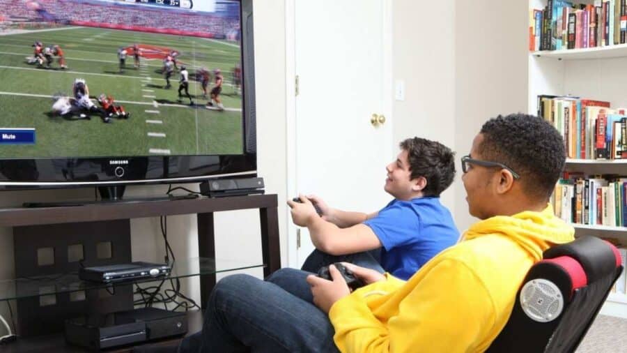 Due ragazzi giocano a un videogioco sportivo su console davanti alla televisione.