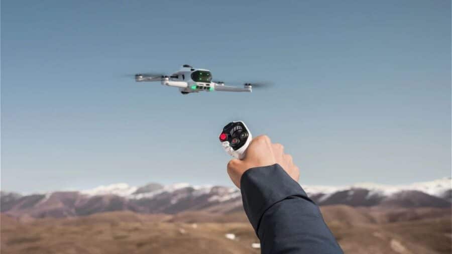 Drone Antigravity A1 in volo sopra un paesaggio aperto, controllato tramite un controller a una mano.