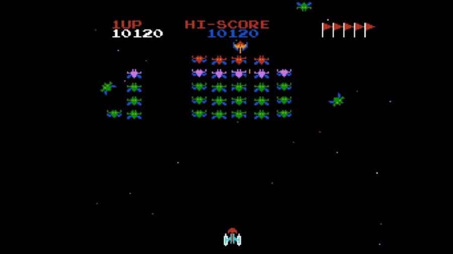 Schermata di un videogioco arcade in stile Galaxian, usato come minigioco durante il caricamento di Ridge Racer su PlayStation.