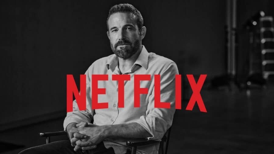 Ritratto in bianco e nero dell'attore e regista Ben Affleck seduto su una sedia da regista, sovrapposto al grande logo rosso di Netflix.