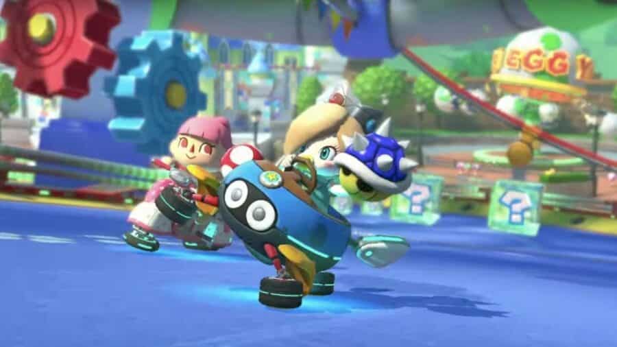 Rosalinda viene colpita da un Guscio Blu durante una corsa in Mario Kart, con altri personaggi alle sue spalle su un circuito colorato.