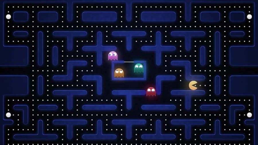 Schermata di gioco classica di Pac-Man in formato widescreen, che mostra il celebre labirinto blu, i puntini da mangiare e i quattro fantasmini colorati pronti a inseguire l'eroe giallo.