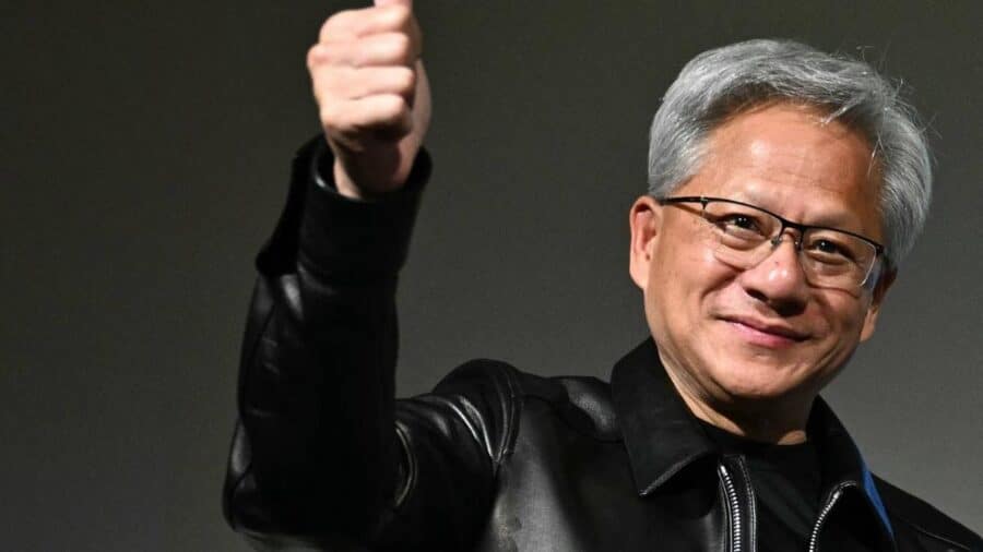 Jensen Huang, CEO di Nvidia, indossa la sua iconica giacca di pelle nera e sorride mentre solleva il pugno con il pollice in alto durante un evento pubblico.