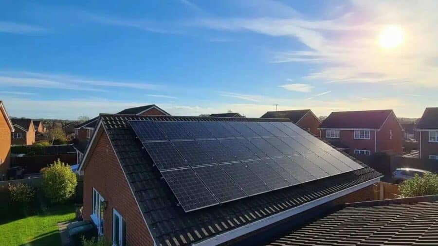 Tetto di un'abitazione residenziale ricoperto da un impianto di pannelli solari fotovoltaici sotto un cielo sereno e un sole splendente.