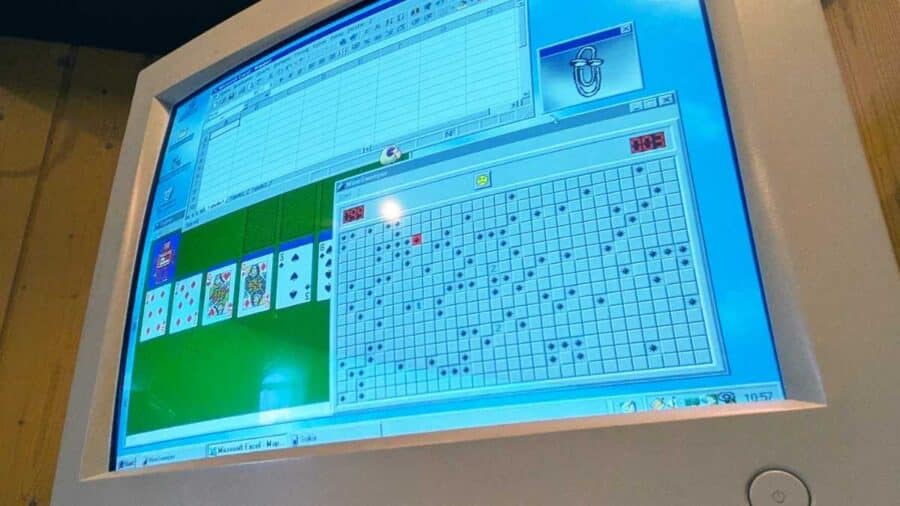 Vecchio monitor a tubo catodico che mostra il desktop classico di Windows anni '90, con i giochi Solitario e Campo Minato aperti in due finestre sovrapposte.