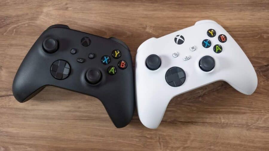 Due controller wireless per Xbox Series X e Series S, uno nero e uno bianco, appoggiati vicini su un tavolo di legno.