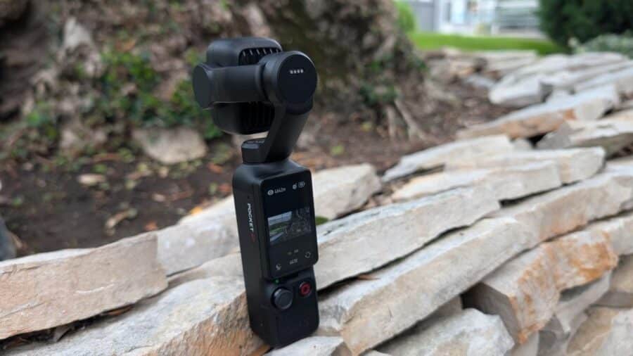 DJI Osmo Pocket 4P appoggiata su un muretto di pietra con schermo touch attivo