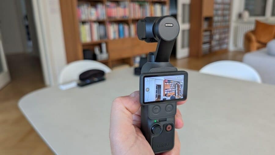 DJI Osmo Pocket 4 impugnata a mano con schermo ruotato e anteprima libreria
