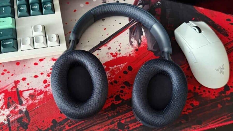 Cuffie MSI Maestro 500 appoggiate piatte su un tappetino rosso e nero da scrivania, che mostrano il rivestimento interno in tessuto a rete dei padiglioni, vicino a un mouse bianco da gaming.