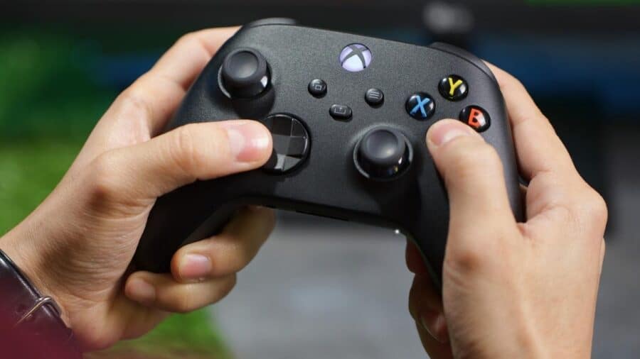 Primo piano ravvicinato delle mani di un videogiocatore che impugna saldamente un controller wireless nero per Xbox Series X/S.