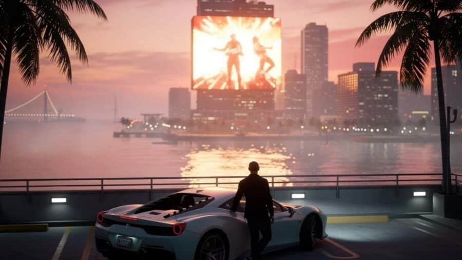 Un uomo in abito scuro è appoggiato a una supercar bianca sul lungomare di Vice City al tramonto, osservando un enorme maxi-schermo luminoso su un grattacielo dall'altra parte della baia.