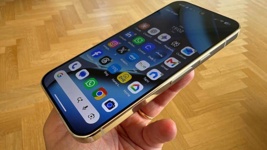 Google Pixel 11 Pro colore oro tenuto in mano, schermo acceso con griglia di app in primo piano.