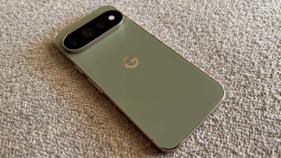 Google Pixel 11 Pro verde oliva appoggiato su una superficie in tessuto, vista posteriore.