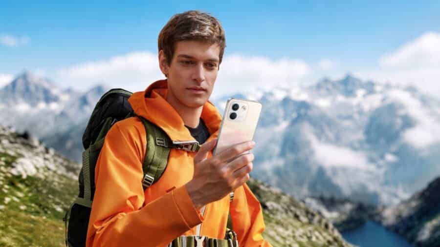 Ragazzo con giacca arancione scatta una foto con Redmi Note 17 tra le montagne innevate