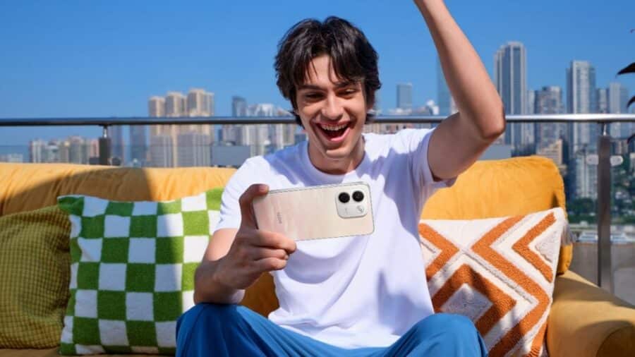 Ragazzo sorridente scatta un selfie con la fotocamera posteriore di Redmi Note 17 su una terrazza panoramica