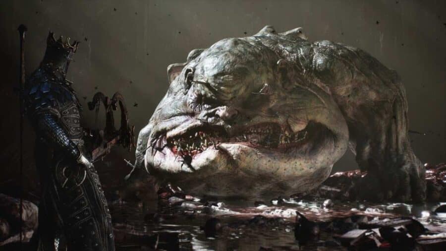 Un cavaliere in armatura oscura fronteggia un gigantesco e mostruoso boss simile a un rospo deforme, caratterizzato da un'enorme bocca zannuta e varie armi umane conficcate nella pelle.