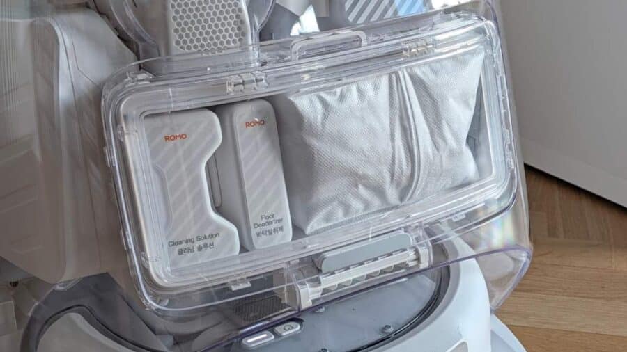 Primo piano dei flaconcini Cleaning Solution e Floor Deodorizer inseriti nella base station, con il sacchetto raccoglipolvere sullo sfondo.
