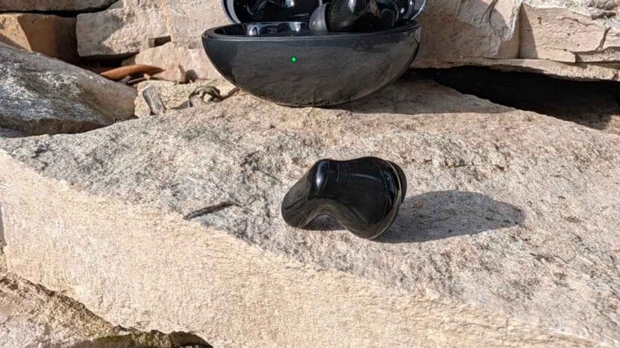 Huawei FreeBuds Neo, un auricolare accanto alla custodia con LED verde acceso