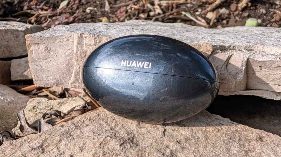 Custodia chiusa Huawei FreeBuds Neo a forma di uovo su rocce, logo Huawei