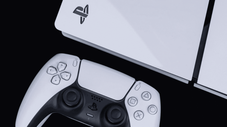 Controller DualSense bianco e nero posizionato in primo piano accanto alla scocca superiore della console PlayStation 5 con il logo PS inciso, su sfondo nero.