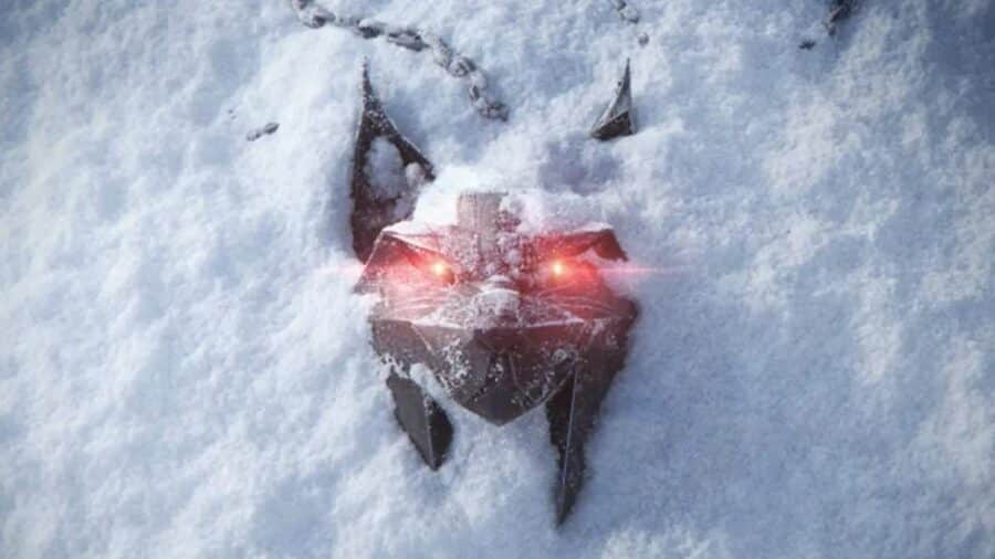 Il medaglione metallico da strigo a forma di lince parzialmente sepolto nella neve fresca con occhi illuminati di luce rossa brillante.