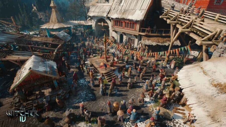 Vista dall'alto di una piazza cittadina medievale gremita di decine di abitanti attorno a un palco di legno tra case innevate e festoni, con il logo The Witcher IV in basso a sinistra.