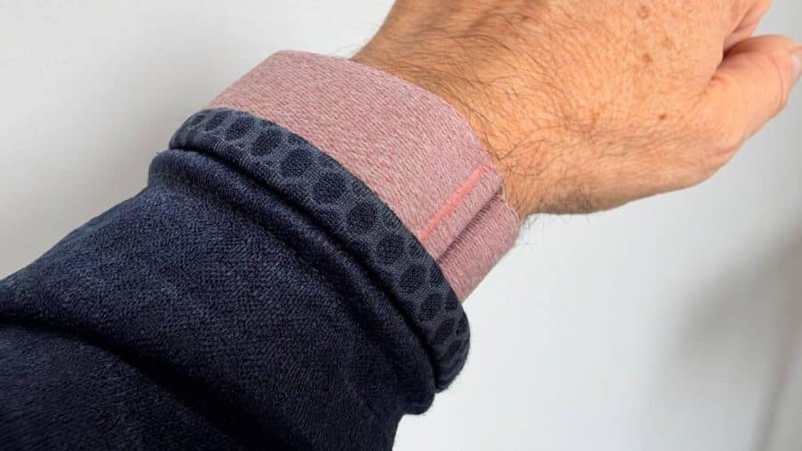 Polso con fascia Mauve della Garmin Cirqa Smart Band accanto al polsino di una felpa