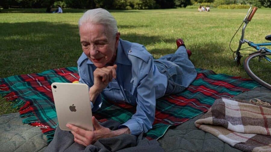 Una persona sdraiata su un prato usa iPad mini