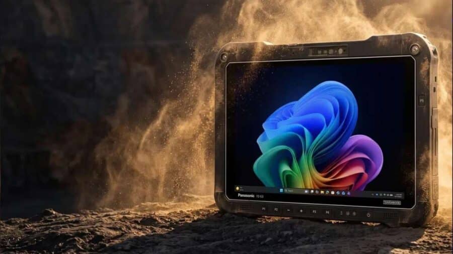 Il tablet rugged Panasonic Toughbook G3 poggiato su un terreno roccioso e sabbioso mentre viene investito da una nube di polvere, con lo schermo acceso che mostra il desktop di Windows 11.
