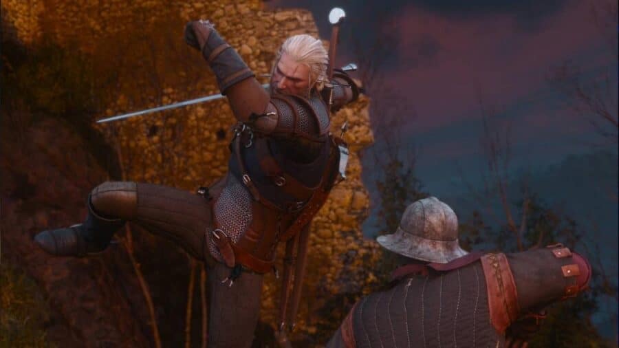 Geralt di Rivia a mezz'aria mentre sferra un fendente con la spada contro una guardia corazzata ai piedi di una fortezza in rovina al crepuscolo.
